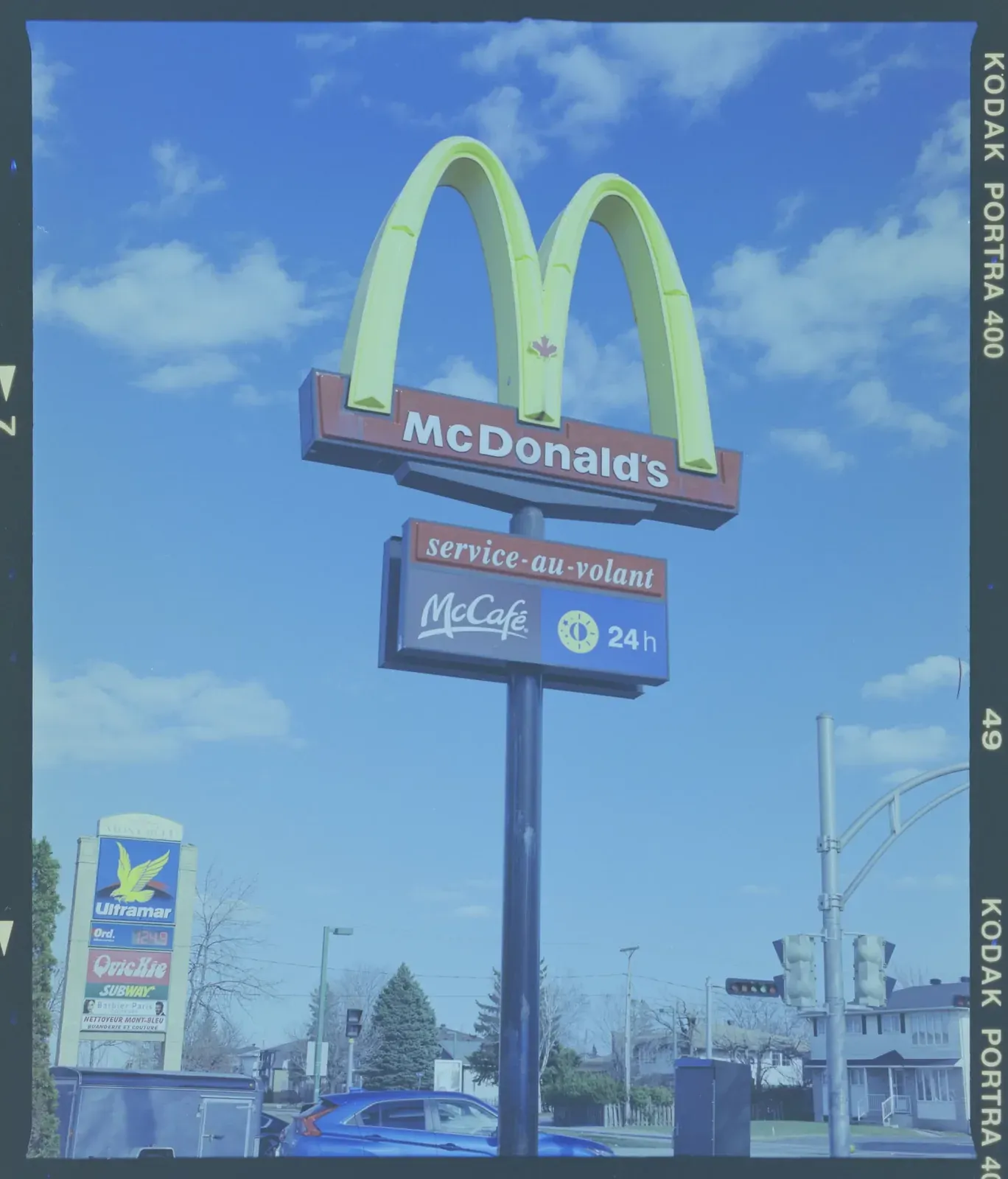 The same frame after a plain invert: the sign is yellow-green, the whole picture is blue-grey and the film edge is dark teal.